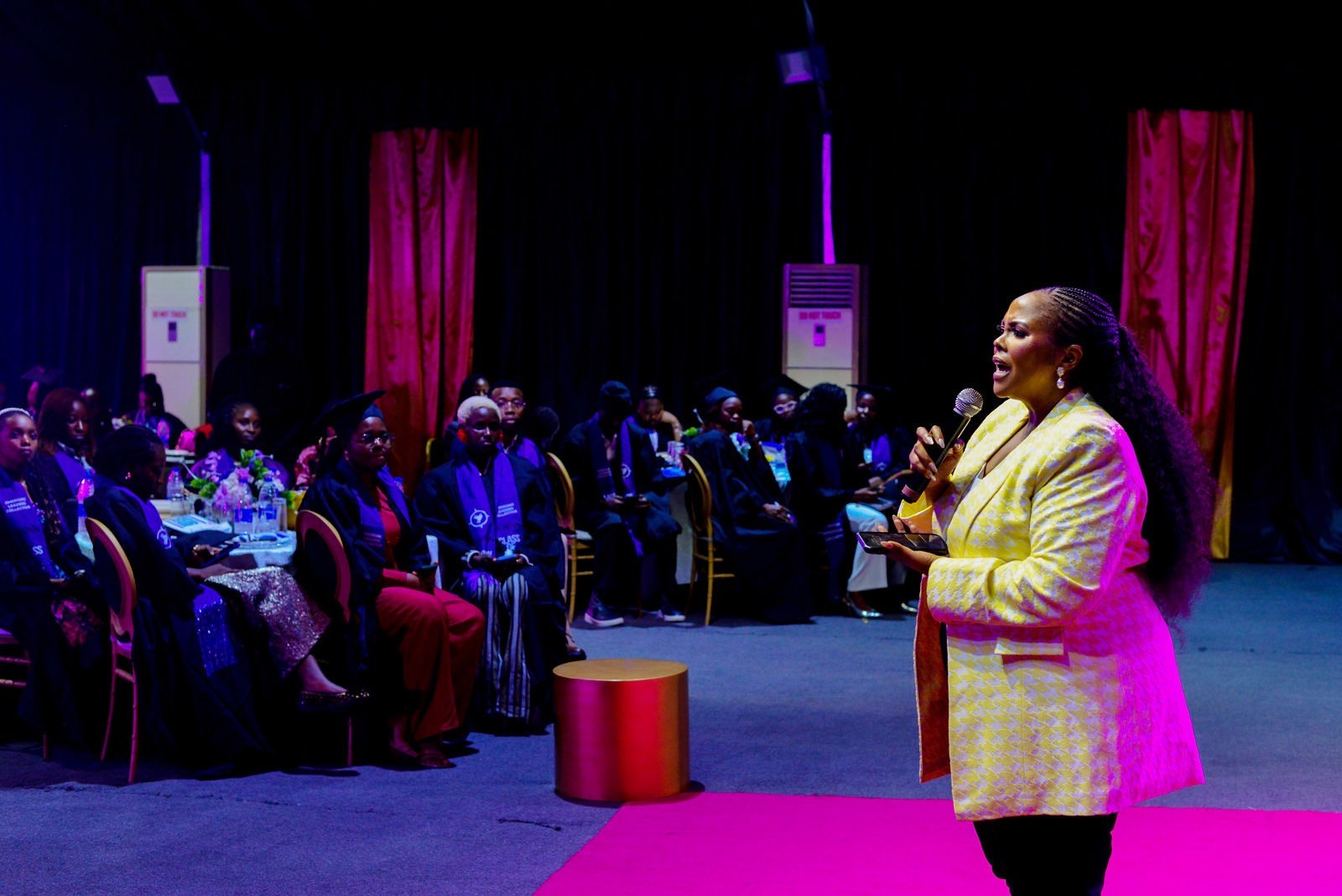 Abosede George-Ogan on stage with a microphone, speaking to a seated audience